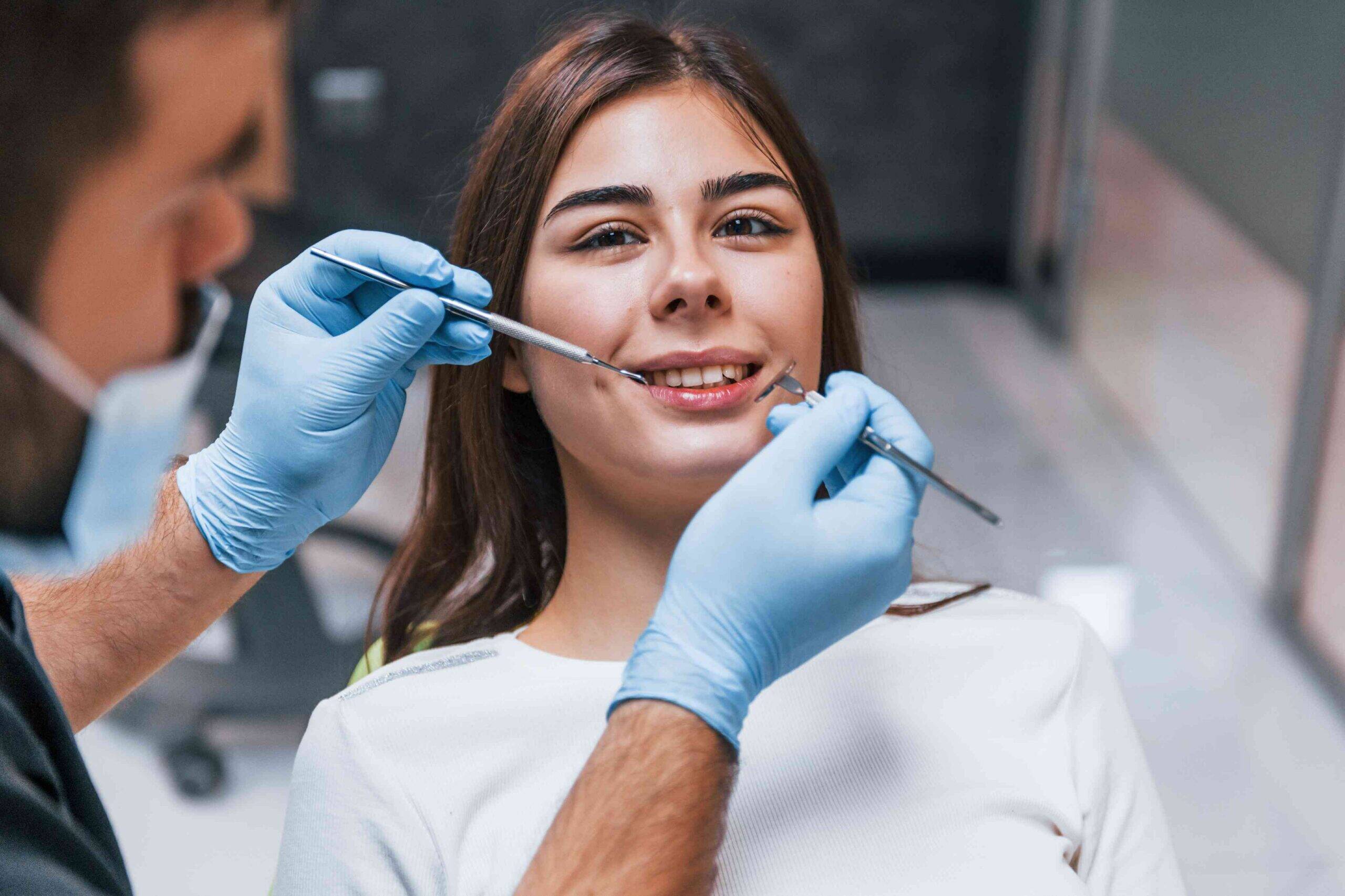 Dentist examining patient’s teeth with dental tools