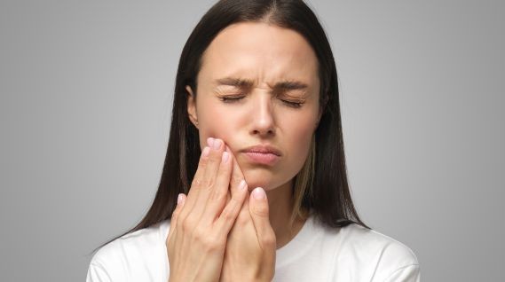 Woman holding her jaw with tooth pain.